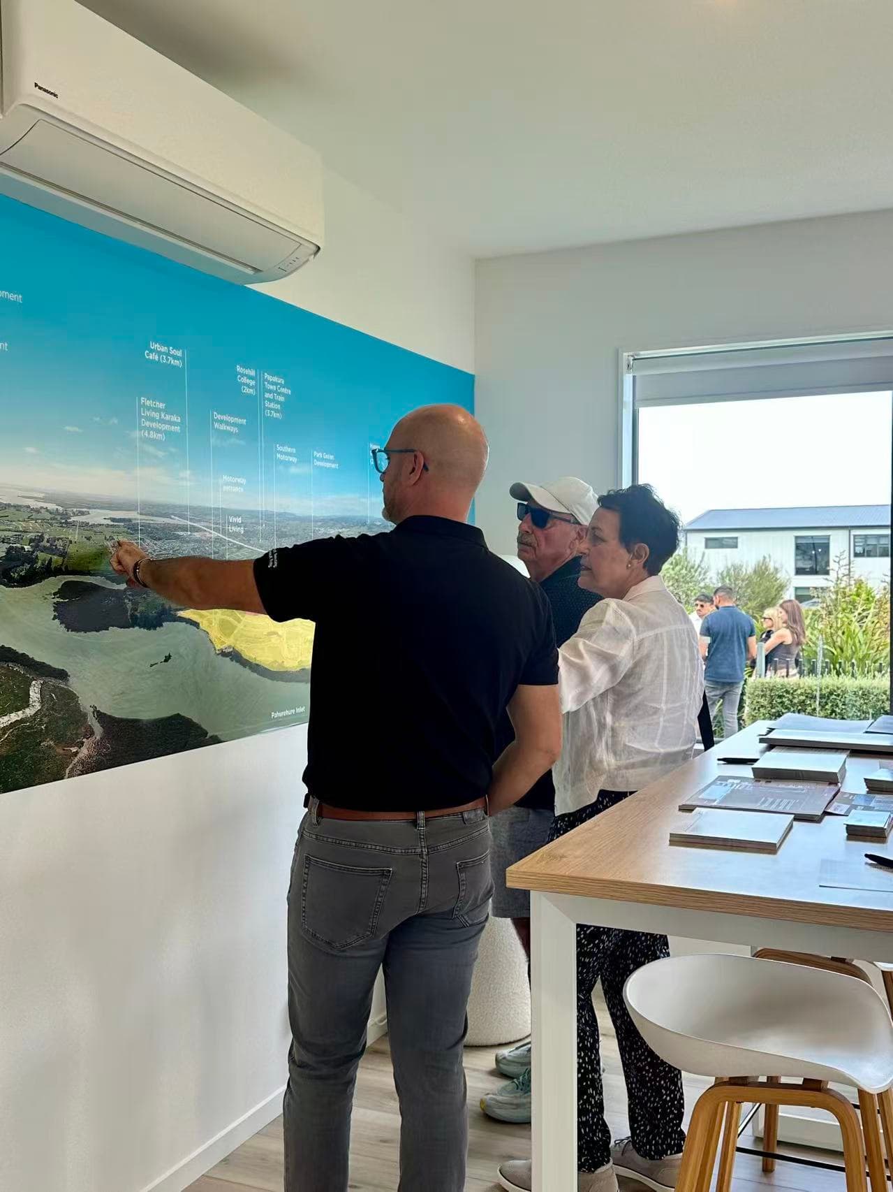 Fletcher Living representative explaining an Auckland development location map to visitors